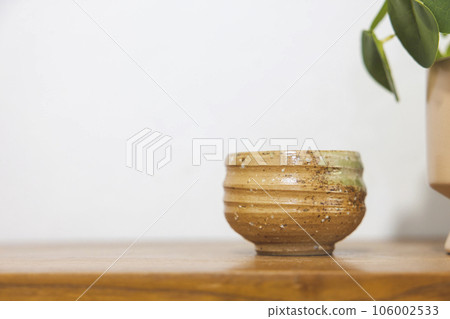 Satai Modern pottery lies on a wooden shelf against a white wall background. Handmade pottery. Thailand's native handicrafts. 106002533