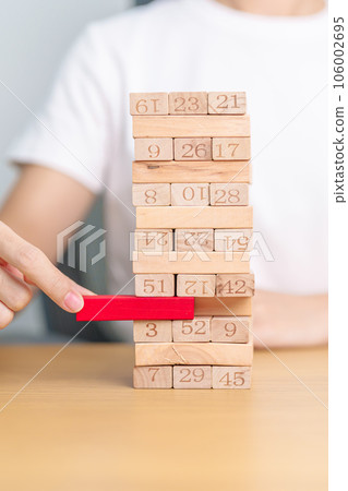 hand pulling wooden block tower on table. Business planning, Risk Management, Solution, leader, strategy, Crisis, falling Business, and Economic recession concept hand pulling wooden block tower on table. Business planning, Risk Management, Solution, leader, strategy, Crisis, falling Business, and Economic recession concept 106002695