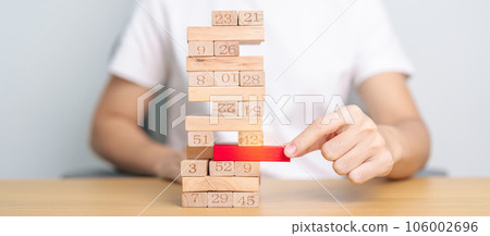 hand pulling wooden block tower on table. Business planning, Risk Management, Solution, leader, strategy, Crisis, falling Business, and Economic recession concept hand pulling wooden block tower on table. Business planning, Risk Management, Solution, leader, strategy, Crisis, falling Business, and Economic recession concept 106002696