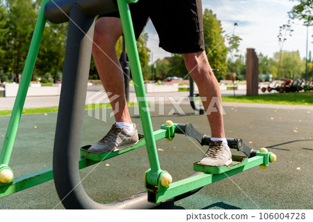 Outdoor fitness equipment creates the perfect environment for fitness. Close-up of male legs in sneakers on a stepper simulator Outdoor fitness equipment creates the perfect environment for fitness. Close-up of male legs in sneakers on a stepper simulator 106004728