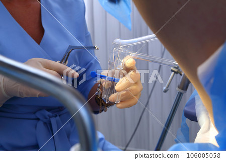 A gynecologist performs a cervical biopsy. Gynecological chair. A woman at the gynecologist for a check-up. A gynecologist performs a cervical biopsy. Gynecological chair. A woman at the gynecologist for a check-up. 106005058