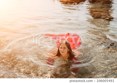 Woman travel sea. Happy tourist in red dress enjoy taking picture outdoors for memories. Woman traveler posing in sea beach, surrounded by volcanic mountains, sharing travel adventure journey 106005491