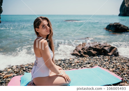 Woman sea fitness. Happy woman with long hair, fitness instructor in white bikini doing stretching and pilates on yoga mat near the sea. Female fitness yoga routine concept. Healthy lifestyle. 106005493