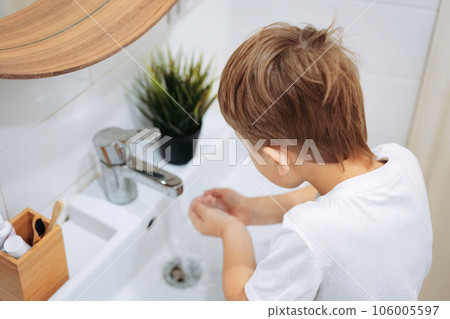 cute 6 years old boy washing his face over the sink in bathroom. Image with selective focus 106005597