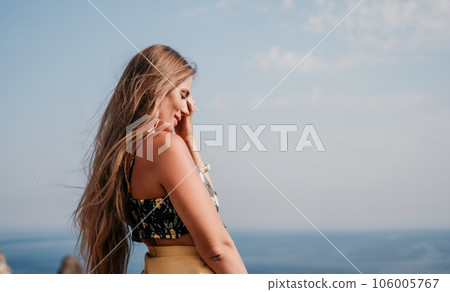 Woman travel sea. Happy tourist taking picture outdoors for memories. Woman traveler looks at the edge of the cliff on the sea bay of mountains, sharing travel adventure journey 106005767