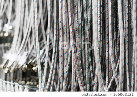 Closed up braided stainless steel texture of flexible hose arranged in a row against white wall. 106008121