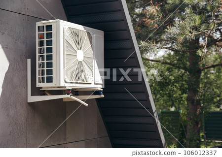 External unit of an air conditioner on facade of small wooden forest house External unit of an air conditioner on facade of small wooden forest house 106012337