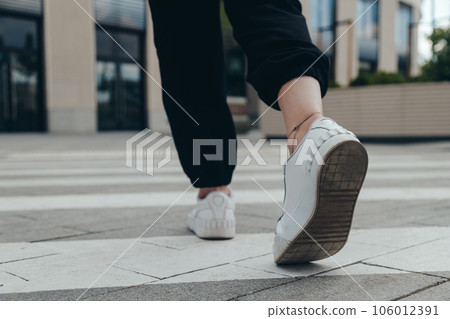 Legs of a girl in White Leather Sneakers Crosses the Street on a Pedestrian Crossing 106012391
