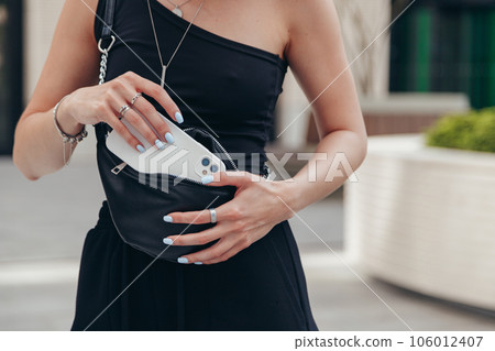 Young Woman puts her Mobile Phone in a Zippered Fanny Pack to prevent Theft Young Woman puts her Mobile Phone in a Zippered Fanny Pack to prevent Theft 106012407