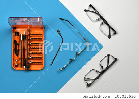 Set of screwdriver bits for repair reading glasses isolated on blue background. Set of screwdriver bits for repair reading glasses isolated on blue background. 106013636