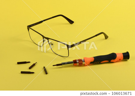 Set of screwdriver bits for repair reading glasses isolated on yellow background. Set of screwdriver bits for repair reading glasses isolated on yellow background. 106013671