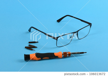 Set of screwdriver bits for repair reading glasses isolated on blue background. Set of screwdriver bits for repair reading glasses isolated on blue background. 106013672
