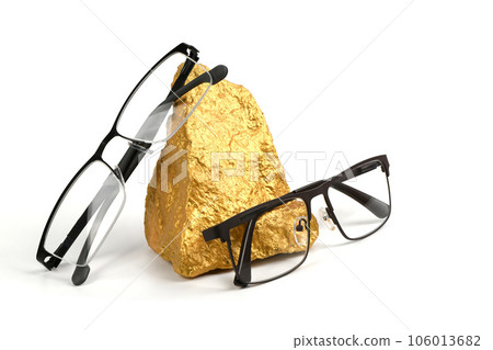 Pair of reading glasses on shining golden nuggets isolated on white background Pair of reading glasses on shining golden nuggets isolated on white background 106013682