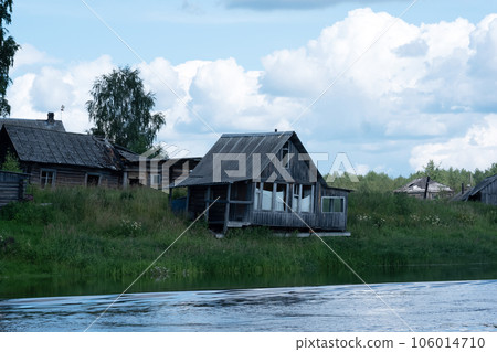 derelict village on the river bank, abandoned wooden houses with empty windows 106014710