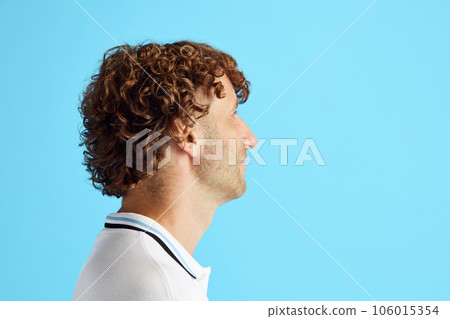 Side view image if curly mature man with bristle face looking straight against blue studio background 106015354