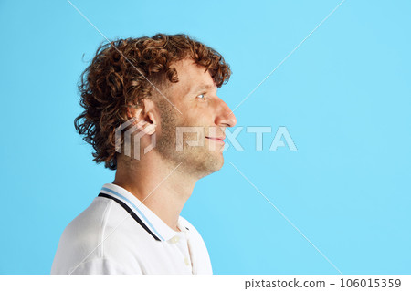Side view image if curly mature man with bristle face looking straight against blue studio background 106015359