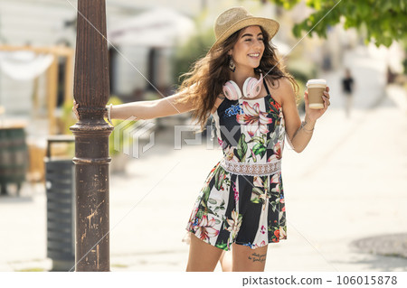 Young beautiful woman with coffee and headphones enjoying a hot summer day 106015878