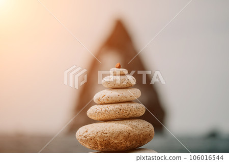 balanced rock pyramid stands tall on sea pebble beach. Selective focus highlights zen stones on the beach, evoking feelings of calm, harmony, and balance. Perfect for meditation or spa concepts. balanced rock pyramid stands tall on sea pebble beach. Selective focus highlights zen stones on the beach, evoking feelings of calm, harmony, and balance. Perfect for meditation or spa concepts. 106016544