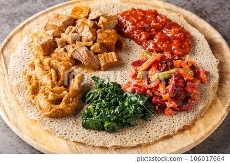 Ethiopian Injera flat bread with various vegetable and meat fillings close up on the wooden board. Horizontal Ethiopian Injera flat bread with various vegetable and meat fillings close up on the wooden board. Horizontal 106017664