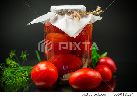 Canned ripe red tomatoes with spices in a large glass jar. 106018134