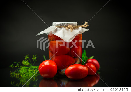 Canned ripe red tomatoes with spices in a large glass jar. 106018135