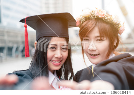 Two young asian girl reach hands selfie a photo of Graduates of Bachelor's degree Two young asian girl reach hands selfie a photo of Graduates of Bachelor's degree 106018414