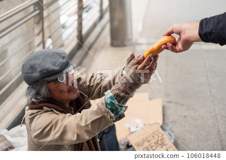 Aged homeless beggar reach out to get bread on donor hand at the bridge 106018448