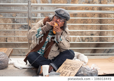 Aged homeless begger eating bread on the bridge 106018449