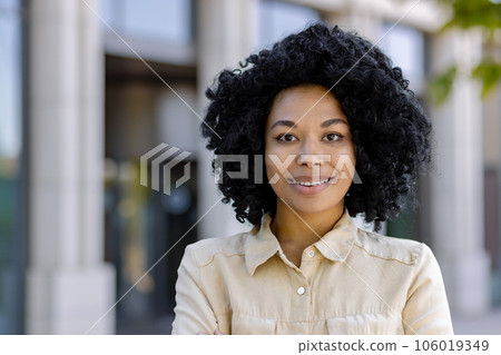 Close-up portrait of an African American woman, a businesswoman smiling and looking at the camera from outside an office building. Close-up portrait of an African American woman, a businesswoman smiling and looking at the camera from outside an office building. 106019349