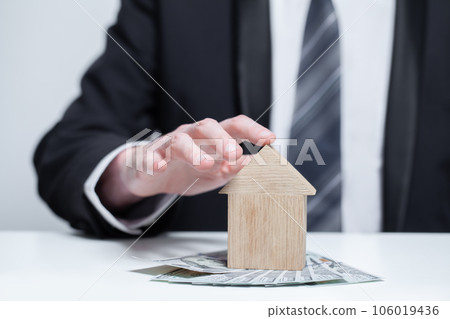 Two wooden houses and us money dollars under it. Byuing property, security, insurance concept Two wooden houses and us money dollars under it. Byuing property, security, insurance concept 106019436