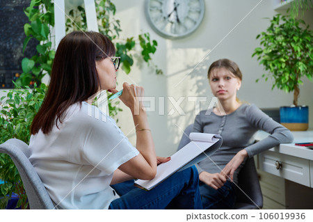 Sad teenage girl at therapy meeting with psychologist 106019936