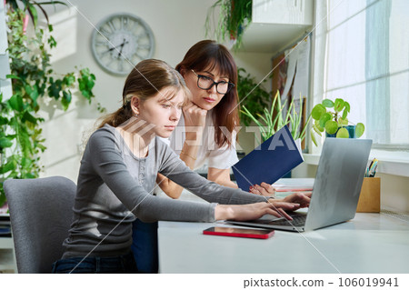 Mother and preteen daughter looking i laptop together, girl typing on keyboard Mother and preteen daughter looking i laptop together, girl typing on keyboard 106019941