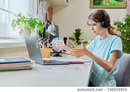 Preteen girl in headphones having video lesson on laptop, at home Preteen girl in headphones having video lesson on laptop, at home 106019954