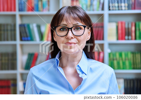 Headshot portrait of middle aged female teacher inside educational building Headshot portrait of middle aged female teacher inside educational building 106020086