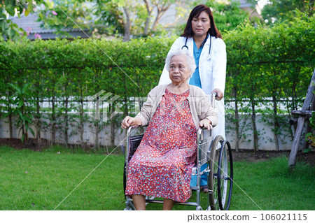 Doctor help Asian elderly woman disability patient sitting on wheelchair in park, medical concept. 106021115
