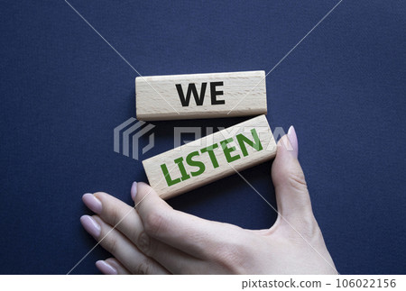 We listen symbol. Wooden blocks with words We listen. Businessman hand. Beautiful deep blue background. Business and We listen concept. Copy space. 106022156