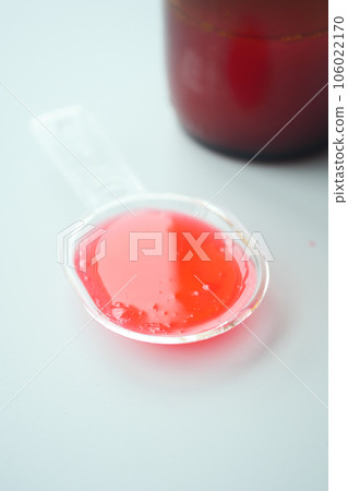 liquid medicine syrup on a plastic spoon on white background  106022170