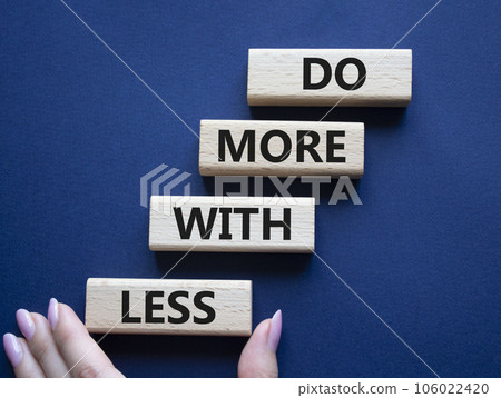 Do more with less symbol. Concept words Do more with less on wooden blocks. Beautiful deep blue background. Businessman hand. Business and Do more with less concept. Copy space. 106022420