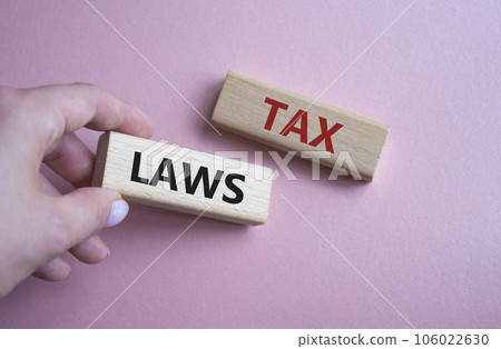 Tax Laws symbol. Concept word Tax Laws on wooden blocks. Businessman hand. Beautiful pink background. Business and Tax Laws concept. Copy space 106022630