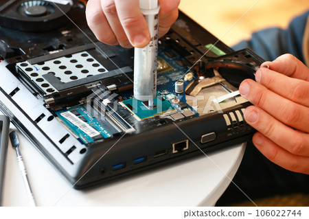 Hand a repairman uses thermal paste syringe apply thermal compound to a CPU. Master replaces thermal grease. Professional service and repair tech and electronics devices, laptops and PC Hand a repairman uses thermal paste syringe apply thermal compound to a CPU. Master replaces thermal grease. Professional service and repair tech and electronics devices, laptops and PC 106022744