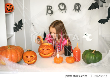 A child dressed up for Halloween looks inside a Jack-o'-lantern carved pumpkin. Preparing for the holiday 106023334