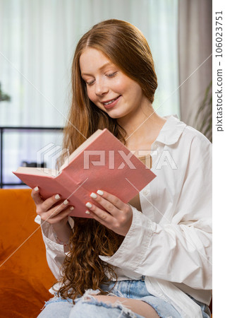 Teen girl relaxing interesting book turning pages smiling enjoying literature taking a rest on sofa Teen girl relaxing interesting book turning pages smiling enjoying literature taking a rest on sofa 106023751