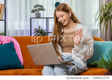 Teenager red hair girl sitting on home couch, making video conference call with friends or family Teenager red hair girl sitting on home couch, making video conference call with friends or family 106023774
