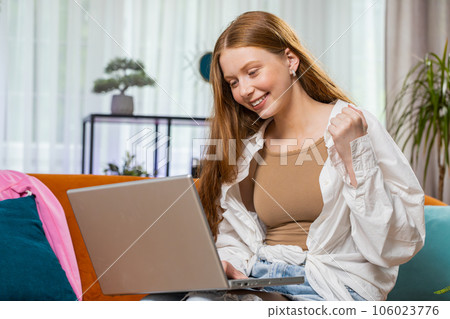 Happy teenager girl working on laptop celebrate success win money in lottery get online good news Happy teenager girl working on laptop celebrate success win money in lottery get online good news 106023776