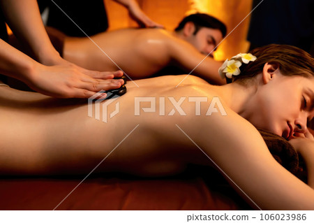 Hot stone massage at spa salon in luxury resort with warm candle light.Quiescent Hot stone massage at spa salon in luxury resort with warm candle light.Quiescent 106023986