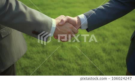 A handshake of two business men against the background of an empty lawn A handshake of two business men against the background of an empty lawn 106024247