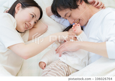 一對夫婦抱著嬰兒在床上睡覺 106026764