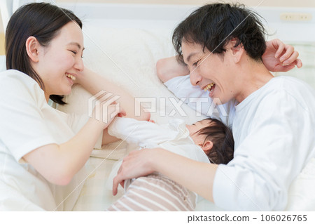 一對夫婦抱著嬰兒在床上睡覺 106026765