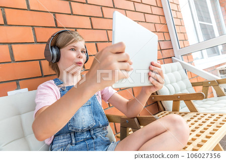 A young girl enjoying listening to music on her headphone with tablet 106027356