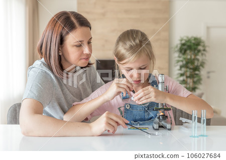 Mother and young daughter doing some experiments with microscope at home Mother and young daughter doing some experiments with microscope at home 106027684